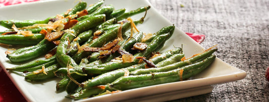 Grilled green beans with crispy onions on a square white serving platter