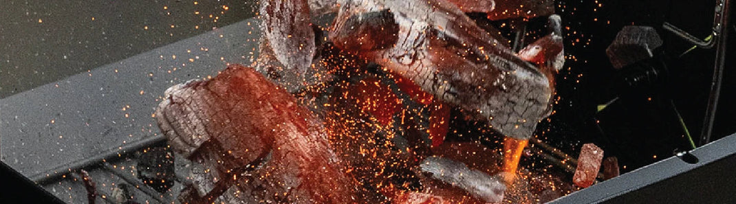 Sparks fly up from a pile of red-hot burning lump charcoal