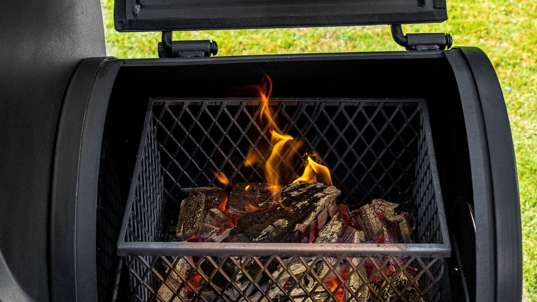 Lump charcoal flames in the basket of an open side fire box