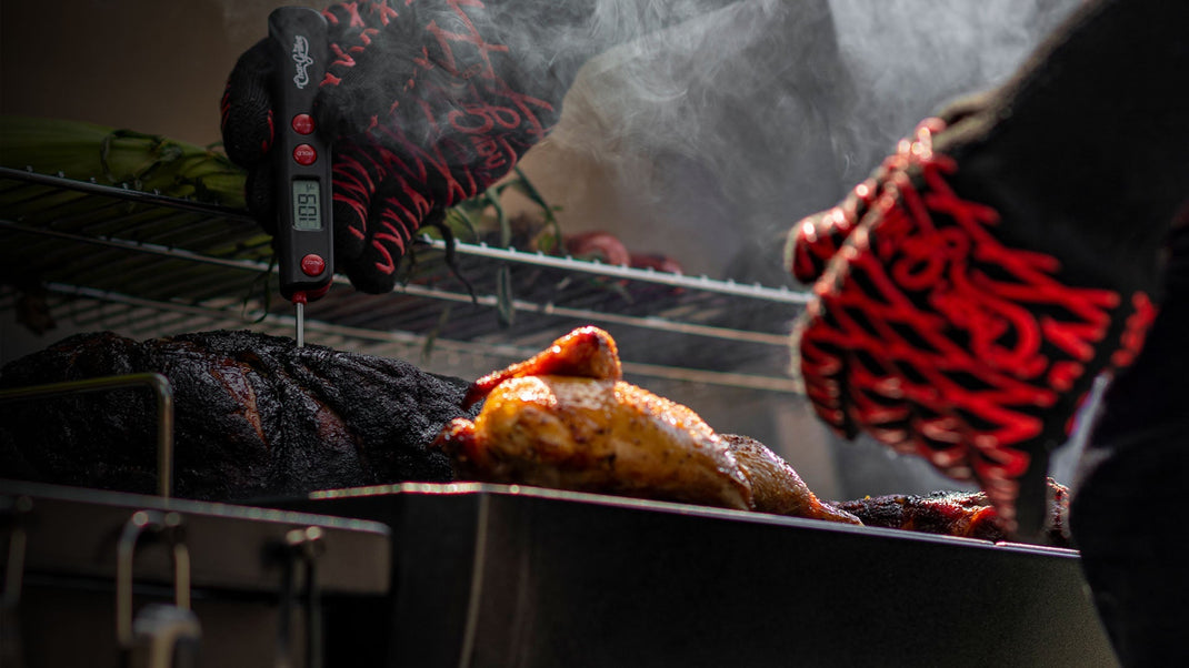 A hand wearing a Char-Griller grill clove reaches into a grill to adjust the position of a half-chicken roasting on the grate