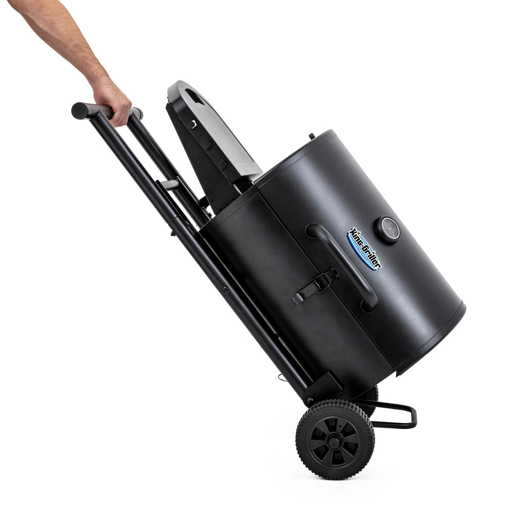 Gambler portable grill collapsed for easy moving. A person holds the handle on the left of the cart and tips the grill up on the wheels on the right of the cart.