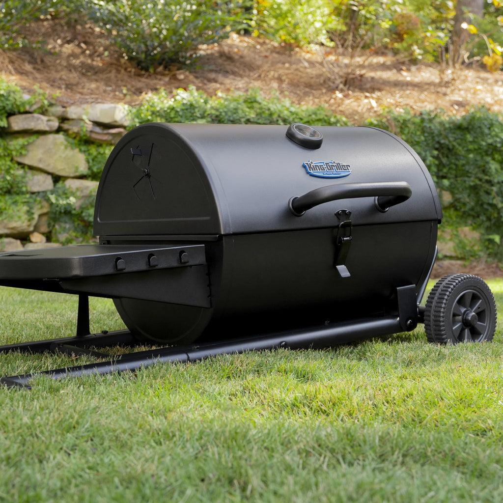 Grill lying flat on the collapsed grill cart. Wheels on the right make moving the grill easy. A latch securely closes the grill.