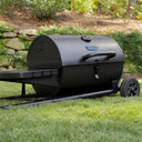 Grill lying flat on the collapsed grill cart. Wheels on the right make moving the grill easy. A latch securely closes the grill.