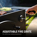 Person using the crank handle mounted in the body of the grill to adjust the fire grate height. Text reads: Adjustable fire grate for control over cooking temperatures.