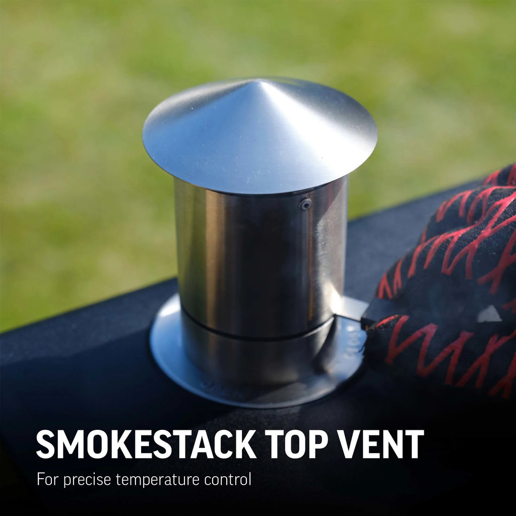 Smokestack top vent for precise temperature control. Metallic smokestack top vent on a grill with grass background. Someone wearing a Char-Griller grill glove adjusts the chimney damper. 