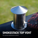 Smokestack top vent for precise temperature control. Metallic smokestack top vent on a grill with grass background. Someone wearing a Char-Griller grill glove adjusts the chimney damper. 