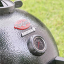 Closeup of the grill lid where the logo plates and dome temperature gauge are mounted.