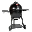 Angled view of the black AKORN kamado grill mounted on a wheeled cart with side shelves up against a white background.