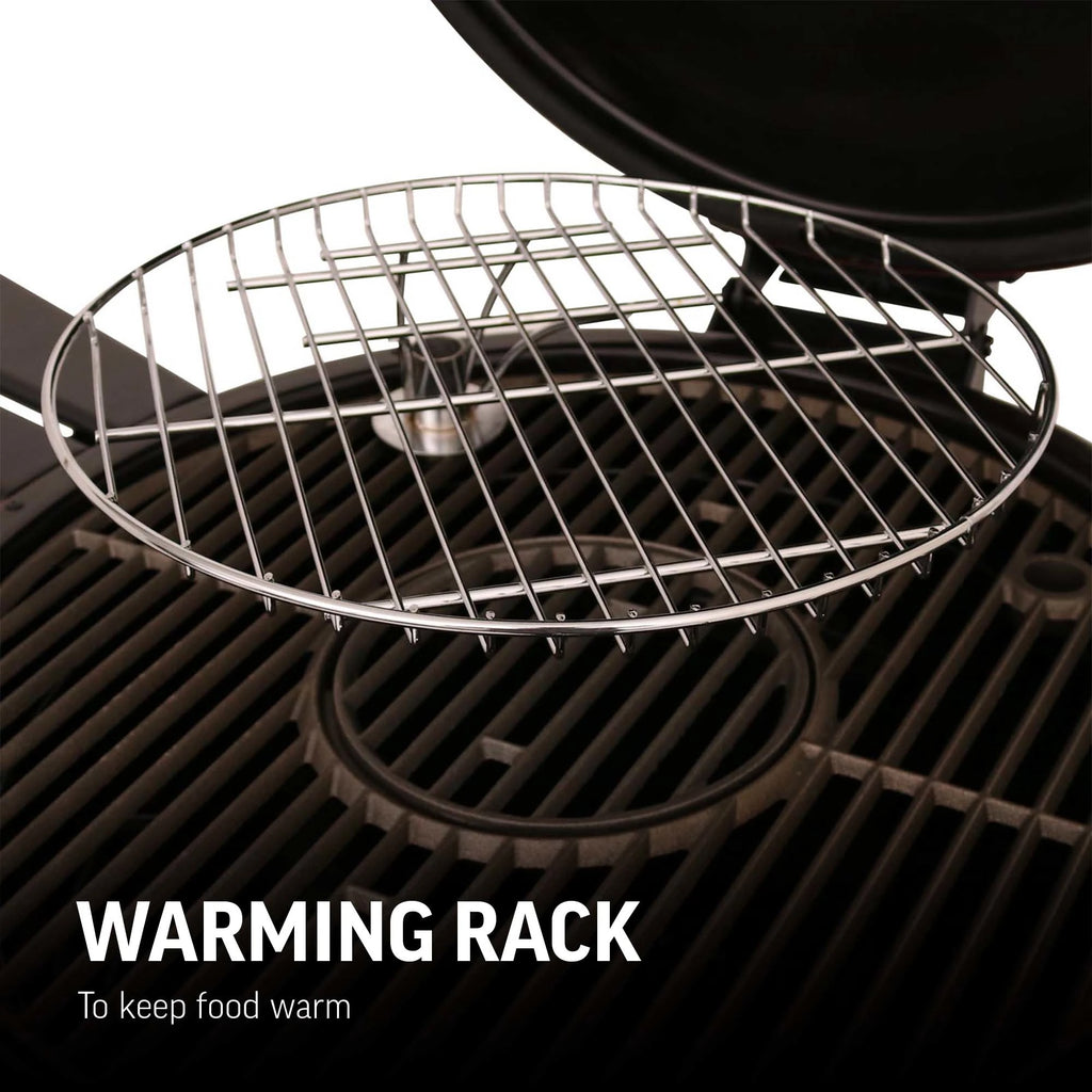 Closeup of the removable warming rack installed in an open AKORN grill. Circular rack has raised edges to stop food falling onto the cooking grate. Text reads: Warming rack to keep food warm.
