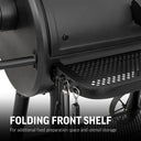 Closeup of the left end of the perforated metal folding front  shelf. The front corner of the shelf is curved. There are 3 utensil hooks build into the left side of the shelf, and the tops of 3 utensils hanging from them are just visible. Text reads: Folding front shelf for additional food preparation space and utensil storage.