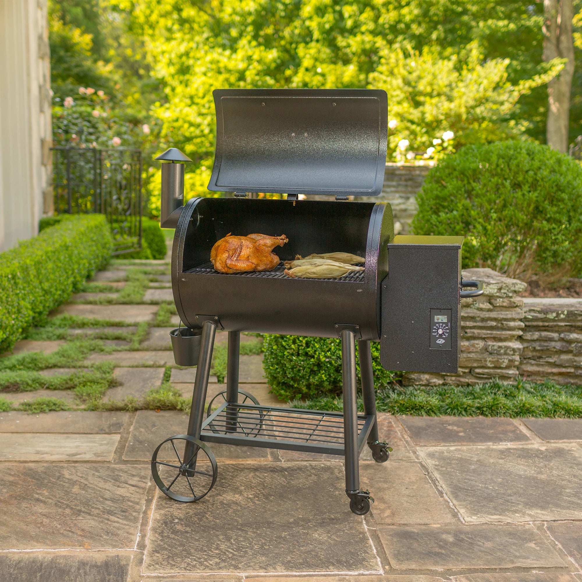 A Wood Pro grill sits open on a paved patio. A whole chicken and several ears of corn sit on the grate.