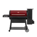 The Gravity Fed 980 barrel charcoal grill, in red, on a white background. The barrel lid is red. The charcoal hopper, cart, and left side shelf are black.