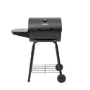 The King-Griller Gambler charcoal grill on a white background. Viewed from the front. The grill has a built-in temperature gauge near the top of the lid, a fixed side shelf on the left, and a cart with 2 wheels for portability.