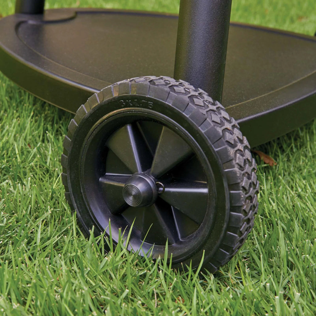 Close-up of a black plastic cart wheel with a treaded tire on the base of the kamado grill leg.