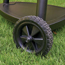 Close-up of a black plastic cart wheel with a treaded tire on the base of the kamado grill leg.