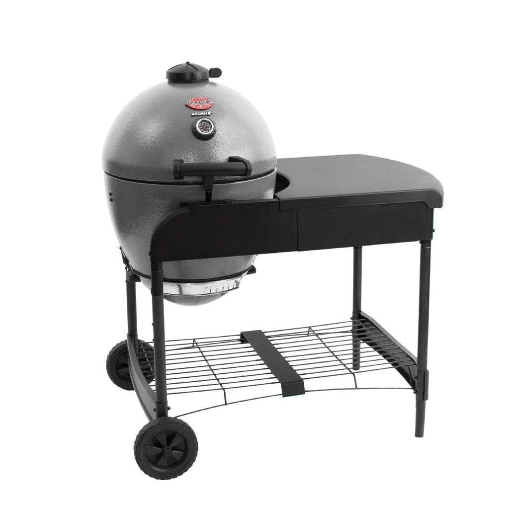 A ash grey Akorn kamado grill in  a cart with a black side table and wheels, shown on a solid white background.