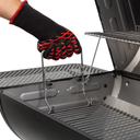 A person wearing a grill glove uses a bailing wire handle to adjust the fire grate height in the barrel grill.