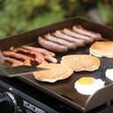 4 strips of bacon, 5 sausages, 3 pancakes, and 2 eggs cook on the griddle.