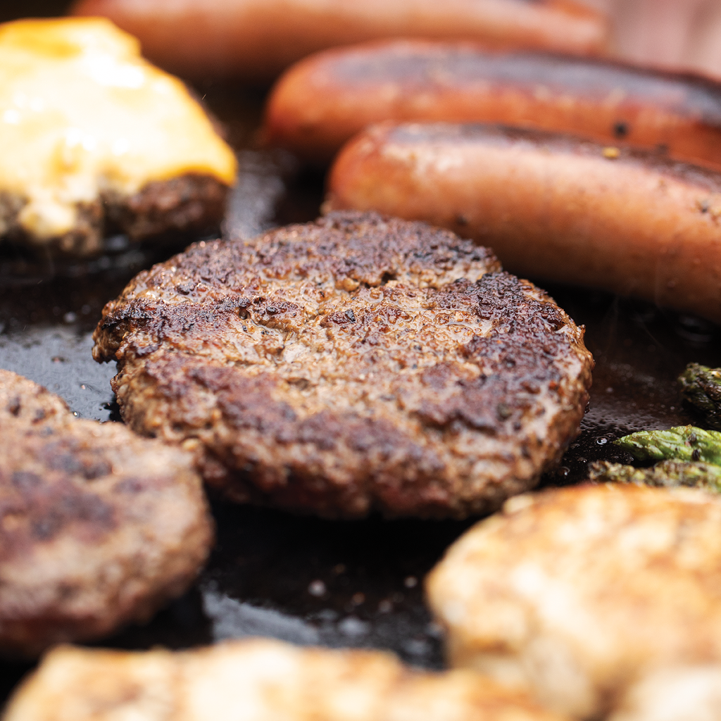 Closeup of grilling hamburgers and sausages